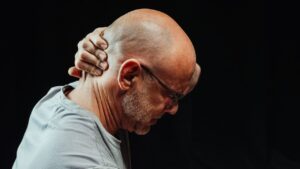 man grabbing the back of his neck in pain