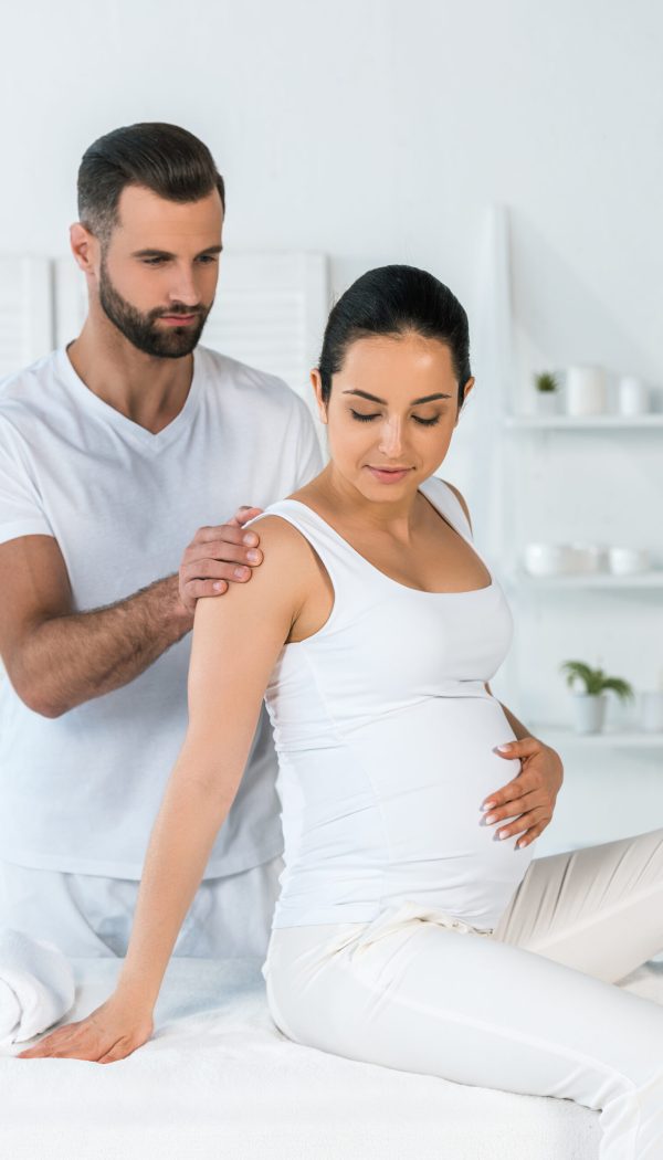 handsome bearded man standing near attractive pregnant woman in spa center