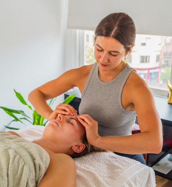A young woman receiving a relaxing facial massage in a bright, modern spa setting.